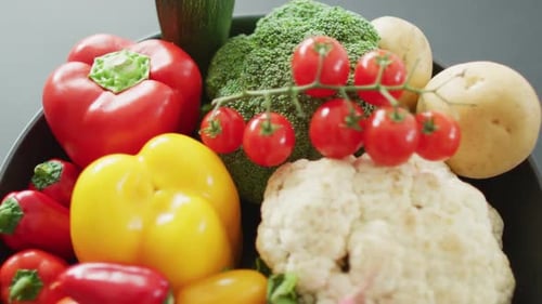 Video of close up of fresh vegetables in pan over grey background