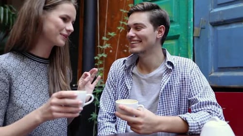 Couple In Cafe. Young People Drinking Coffee And Communicating