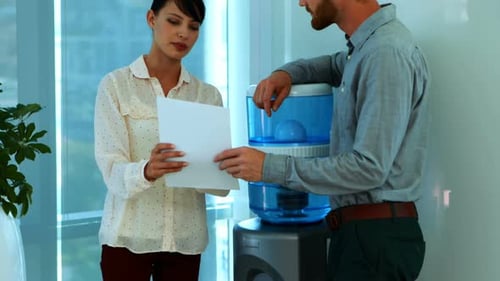 Business Colleagues Discuss Documents Near Water Cooler