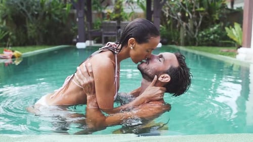 Attractive Couple Kissing in Tropical Swimming Pool