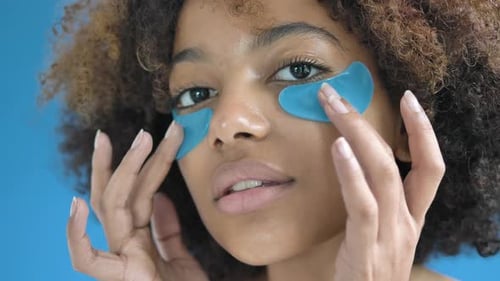 Woman Applying Bright Blue Under-Eye Patches