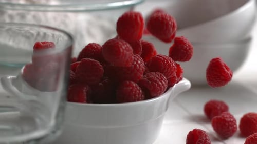 Raspberries Falling into White Bowl in Bright Kitchen