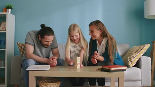 Kleines Mädchen spielt Jenga mit Mama und Papa