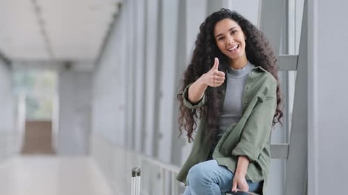 Beautiful Young Hispanic Woman with Curly Hair International Traveler Girl Lady Sitting in Airport