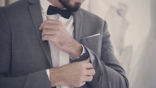 Young Adult Adjusts Bowtie Before a Wedding