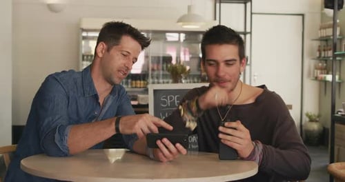 Two Men Talking and Using Phones in Cafe