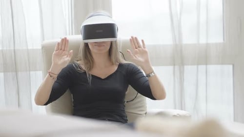 Woman Uses VR Headset Sitting in Chair
