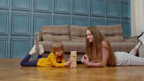 Happy Young Mother Woman Teaching Small Child Daughter Playing Wooden Blocks Board Game at Home