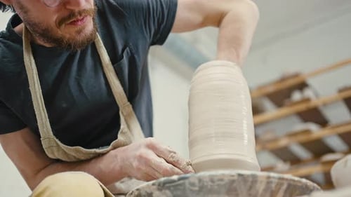 Nahaufnahme eines männlichen Töpferkünstlers, der Keramikvase auf der Töpferscheibe in Zeitlupe unter der Ansicht formt
