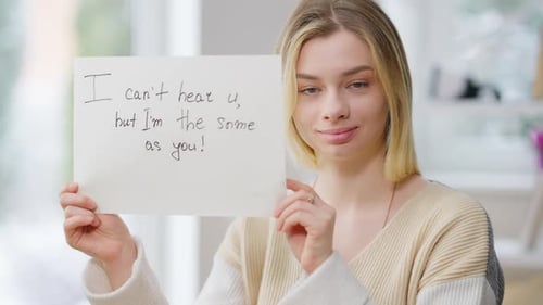 Smiling Deaf Young Woman Showing Paper with I Can't Hear u but I'm the Same As you Written