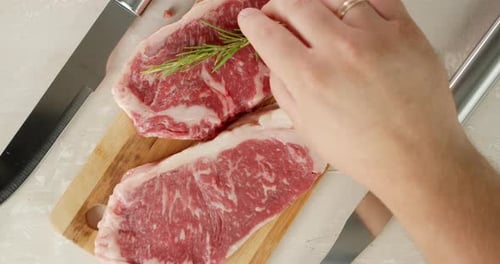 Raw Steaks Seasoned with Rosemary on Cutting Board