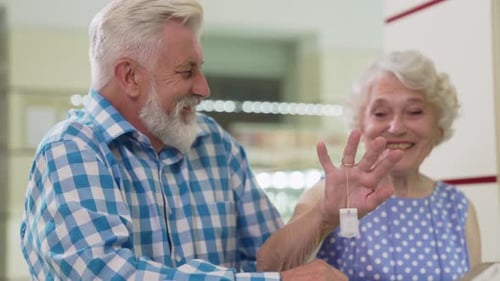 Cheerful Aged Couple Choosing Golden Ring at Jewelry Store