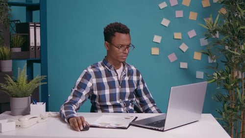 Man Celebrates Success at Desk with Laptop