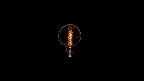 Edison Dirty Lamp with Dust Inside Glass, Flicker on Black Background. Amber Tungsten Color Old