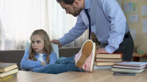 Hija mal portada sentada en la mesa, ignorando los comentarios del padre, conflicto