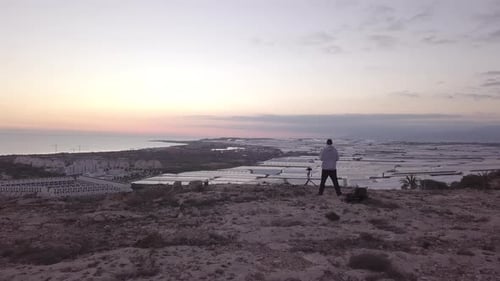 Aerial View Of Man With A Camera On Top Of A Cliff looking the sunset