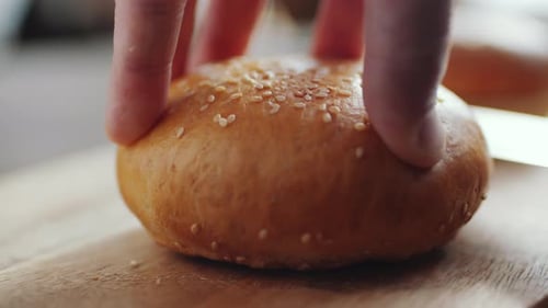 Hand Cuts Sesame Seed Bun with Knife