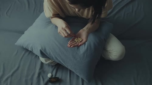 Woman Takes Pills While Sitting on Bed