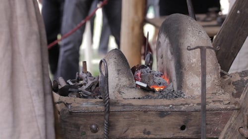 Blacksmith Working a Forge With Tongs