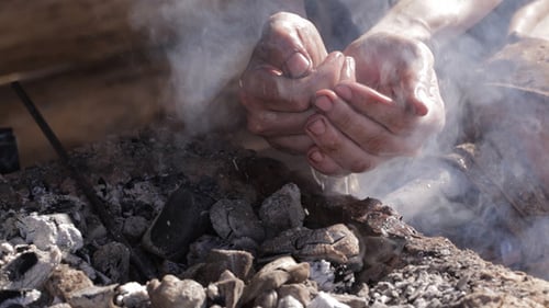 Hands Pouring Water on Burning Charcoals