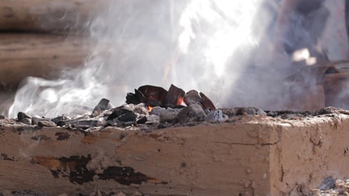 Rustic Furnace Burning Charcoal Outdoors Under White Smoke