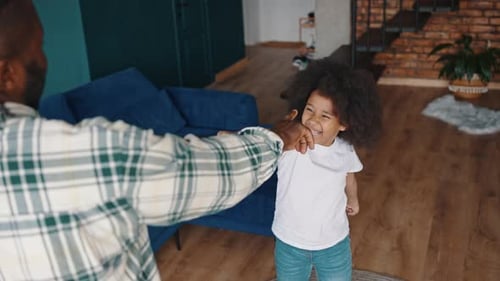 Child and Adult Share a Fun Dance Indoors