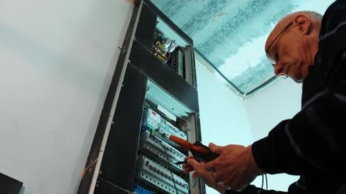 Elektriker testen den elektrischen Strom in der Schalttafel von Hand.