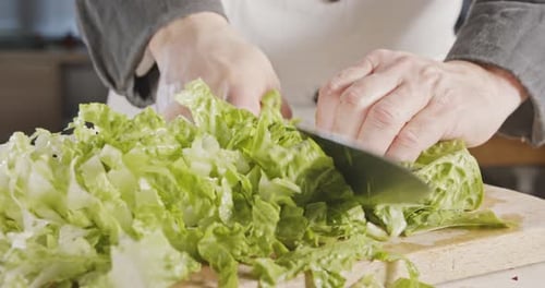 Chef knife cutting green lettuce - close up