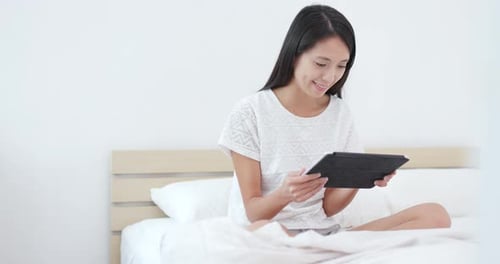 Woman Using Tablet in Bed at Home