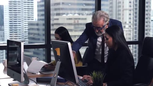 Employees Collaborating on Desktops in Modern Office