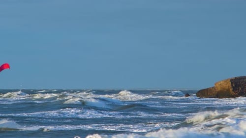 A group of people engaged in kitesurfing in sunny autumn day, high waves, Baltic Sea Karosta beach i