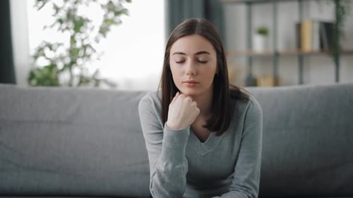 Young Woman Thinking on Couch Indoors