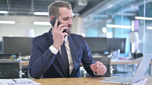 Young Businessman Talking on Smartphone in Office