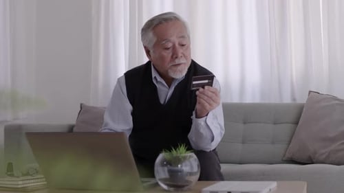Senior Man Using Laptop with Credit Card at Home