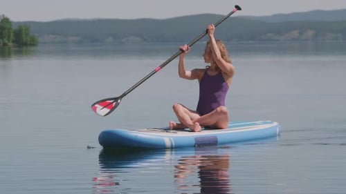 Woman Paddleboarding on a Calm Lake on a Sunny Day