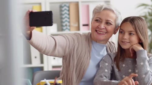 Grandmother and Granddaughter Taking Selfie Indoors