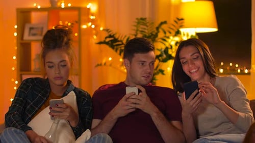 Friends Using Mobile Phones Relaxing on Sofa
