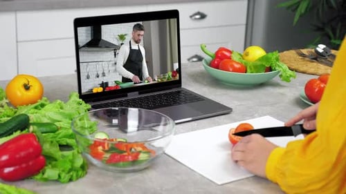 Mujer en la cocina Estudia en línea, videollamada, cámara web, computadora portátil, escucha, el chef le dice al profesor