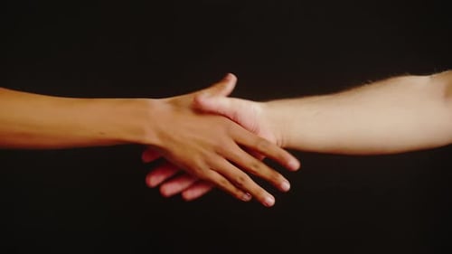 Two People Engage in a Handshake on Black