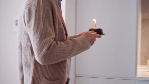 Man Brings Birthday Cake to Smiling Woman