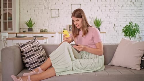 Woman Using Credit Card With Smartphone on Sofa