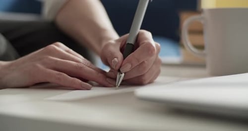 Woman Writing on Paper at Desk Close Up