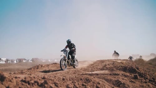 Motocross Racers Riding and Jumping on Dirt Track