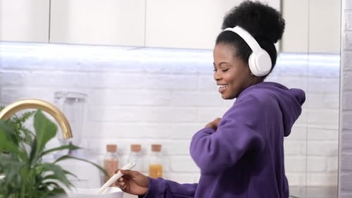 Woman Dances While Cooking with Headphones in Kitchen