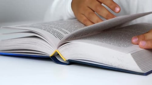 Child Turns Pages in Large Book Close Up