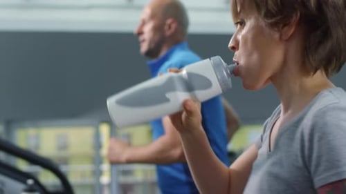 Man and Woman Running on Treadmills in Gym