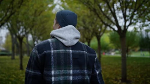 Back View of Young Man Walking in Autumn Park