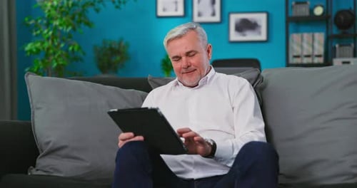 Man Sitting on Couch Using Tablet