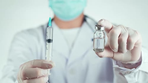Medical Professional Holding Syringe and Vial Close Up