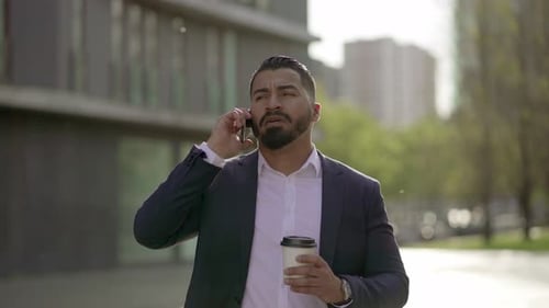 Man in Suit Walks and Talks on Phone